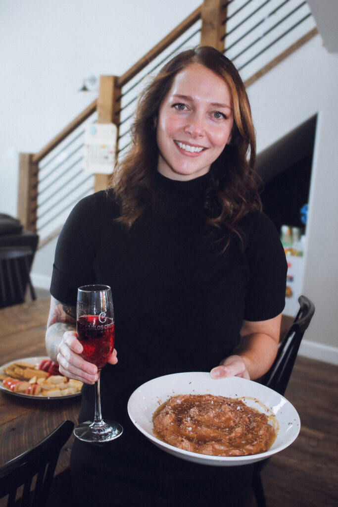 Owner of Carlos Creek stands holding sweet whipped feta and glass of Ruby Minnescato.